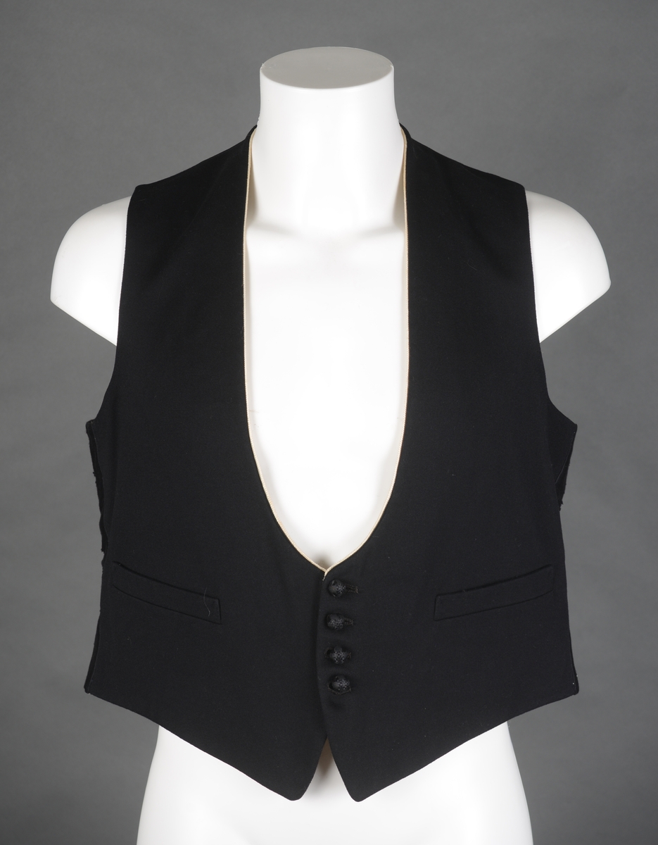 Snippkjole med vest.
Snippkjole i svart ullstoff med slag sydd av satengvevd silkestoff. 1 knapphull på venstre slag. Bakovertrekte skulder- og sidesømmer. 1 innerlomme på høyre framstykke og 1 på venstre. 1 innsnitt og 3 trekte knapper på hver framstykke. Splitt fra livet og ned MB. Dekor 2 trekte knapper i livet ved splitten. Wienersømmer i ryggen og søm MB. Plagget er avtatt i livet. Tosømsermer med lukket splitt med 3 trekte knapper. Plagget har innsydde skulderputer og er helforet. Hempe og firmamerke i nakken. Firmamerke inne i innerlommen på høyre framstykke.
Vest i svart ullstoff på forstykket og satengvevd blankt stoff på ryggen. Spensel med spenne på ryggen, søm MB med en splitt i nedre kant. Vesten er dypt halsrigning og har påsydd et hvitt dekorbånd langs rigningen. Lukkes med 4 trekte knapper. 2 lommer foran. Vesten er foret med hvitt bomullsfor med svarte striper. Samme for som i ermene på snippkjolen. Vesten er antakelig utsydd i sidene en gang.