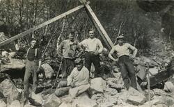 Fem unge arbeidarar attmed ein steinbukk. Biletet er tatt un