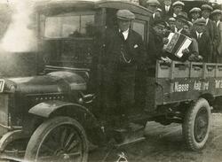 Ein lastebil med fullt av unge menn og gutar på lasteplanet.