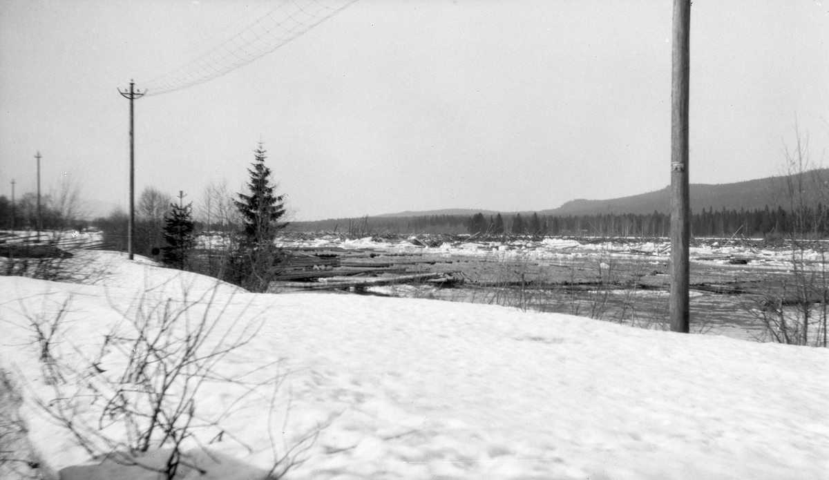 Isgang i Glomma ved Indset, lengst nord i Elverum kommune.  Fotografiet er tatt fra en snødekt vinterveg med lysstolper i brøytekantene.  Nedenfor bakkekammen vegen går på flyter Glomma, der det våren 1928 var en dramatisk isgang. Vi skimter hvordan stømmen og ismassene hadde fått tømmeret til å reise seg.  På grunnene langs land å det fortsatt en del tømmer som ennå ikke var utislått, og som forhåpentligvis fikk ligge i fred for ismassene, slik at det kunne fløtes når elveløpet ble isfritt.  På motsatt side av elva ses ei slette med skog, langt bakenfor denne skogen ligger en åskam, som også er skogkledd.

Befolkningen i bygdene langs Glomma mente at en serie store isganger i andre halvdel av 1920-åra og ved inngangen til 1930-tallet hadde sammenheng med reguleringa av innsjøen Aursunden øverst i vassdraget i 1924. Der magasinerte man vann gjennom sommerhalvåret, for å tappe det ut til beste for kraftverkene nedover i vassdraget gjennom vintersesongen. Høyere vintervannføring førte tilsynelatende også til mer isgang, særlig i vinterhalvåret. Dette førte til en konflikt mellom grunneierne i de hardest rammete områdene og staten, som konsesjonsgivende instans - se fanen "Opplysninger".