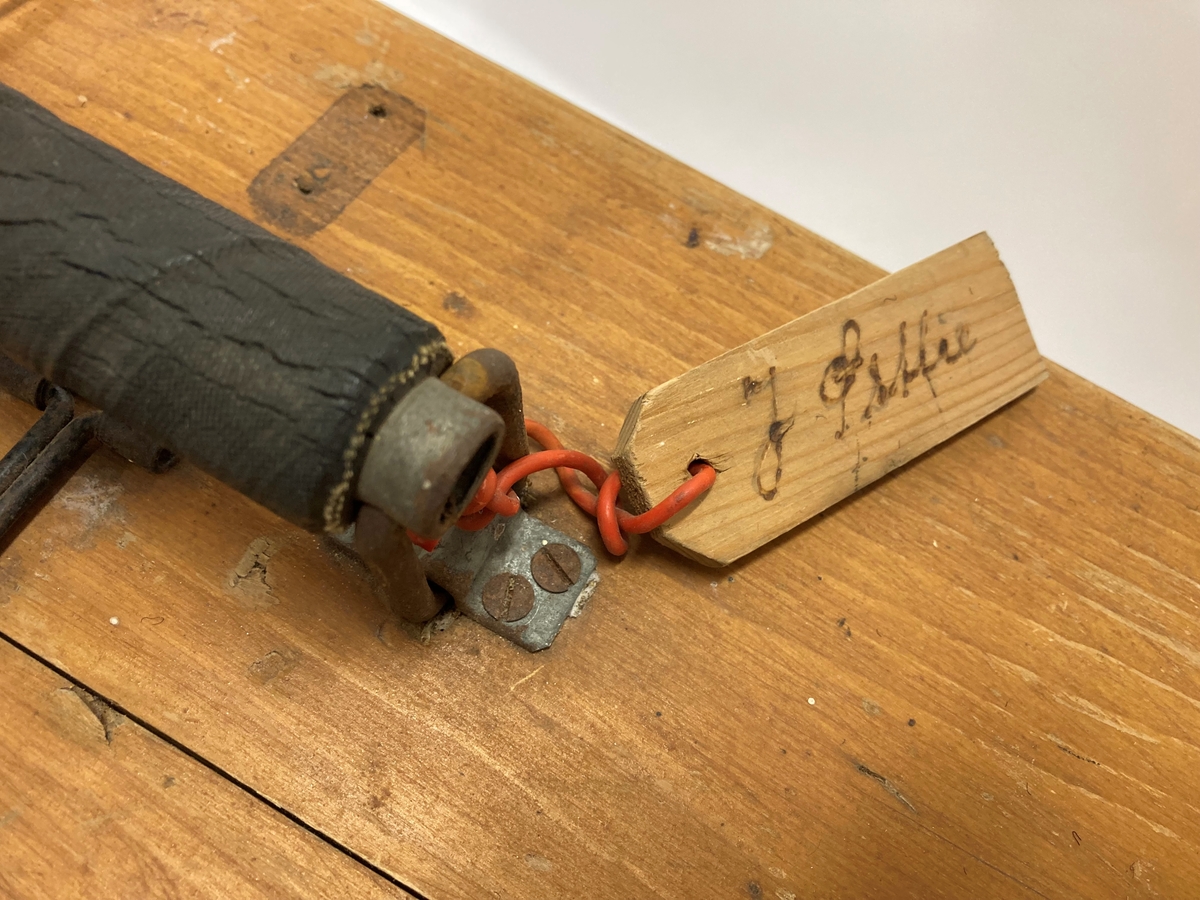 Trekoffert med hengslet lokk. Laget av plater, planker og lister. Metallbeslag i hjørnene. Håndtak på langsiden med vedheftet treskilt merket "8218" på fremsiden og på baksiden J. Østlie. Papiretikett på kortsiden "Halden 183". Kassen inneholder fangedrakten til Johan Østlie, Kornsjø, brukt i Grini fangeleir.