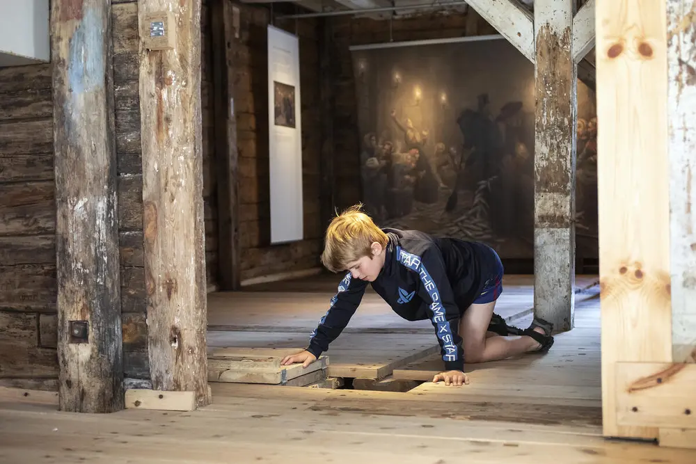 Gutt studerer luken i gulvet i silderommet på Norges Fiskerimuseum