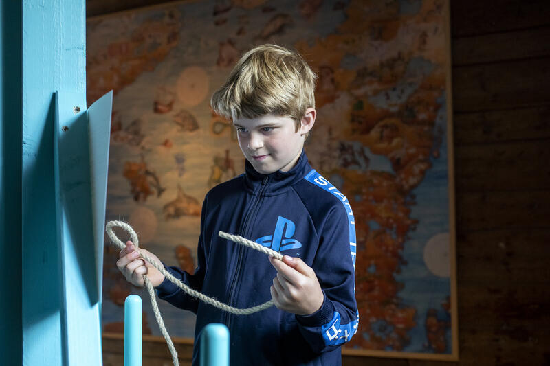 Konsentrert gutt øver på å lage knuter og knop, en aktivitet du kan prøve på Norges Fiskerimuseum