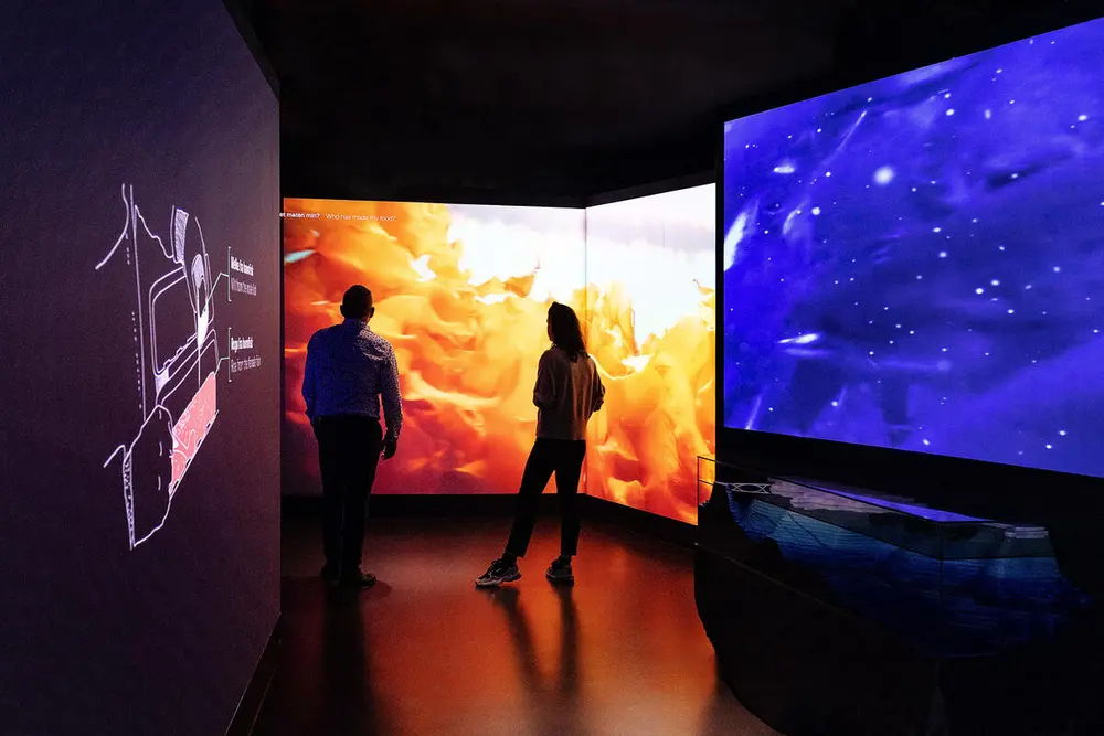 Vi ser to personer som står og ser på utstillingen i Storeblå visningssenter for havbruk