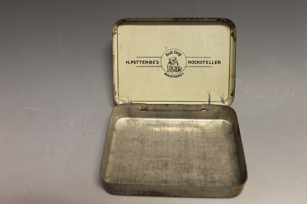 På lokket: AMERICAN GRANULATED PLUD TOBACCO ROCKEFELLER H: PETTERØE KRISTIANIA, inni lokket: H. PETTERØES ROCKEFELLER Bull Dog REGISTRERET, tegning av bulldog