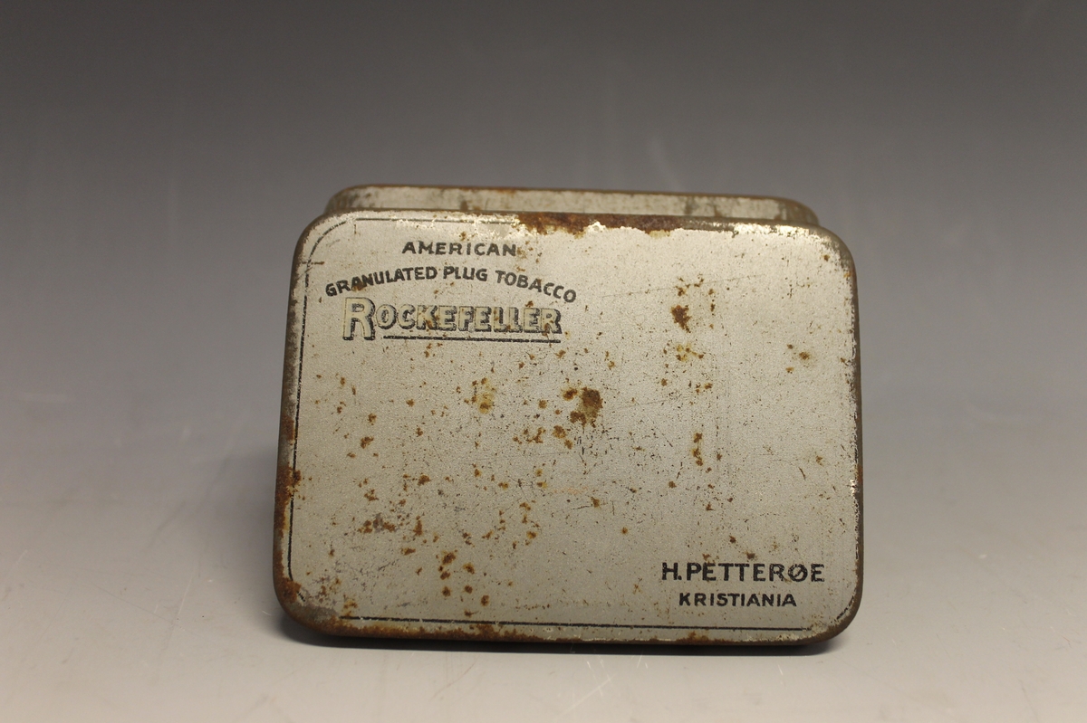 På lokket: AMERICAN GRANULATED PLUD TOBACCO ROCKEFELLER H: PETTERØE KRISTIANIA, inni lokket: H. PETTERØES ROCKEFELLER Bull Dog REGISTRERET, tegning av bulldog