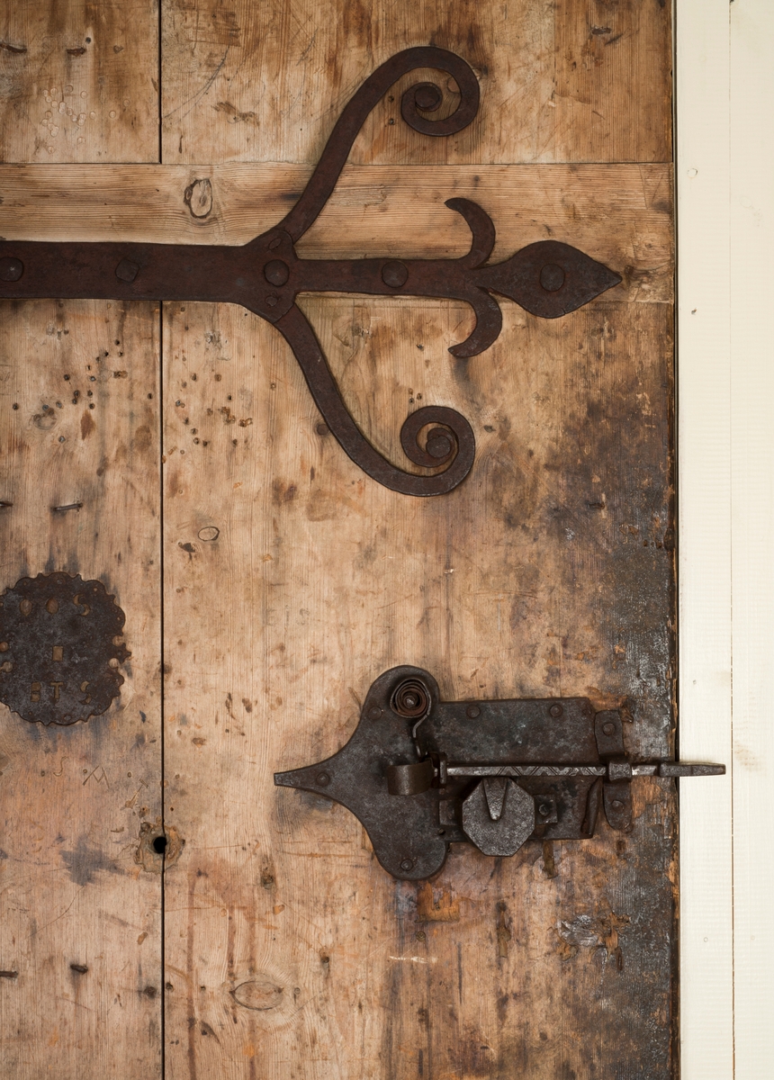 Døra består av tre planker på innsida, satt sammen med dragspon, som senere er høvla ned så døra er helt plan. Har jernbeslag på innsida, over dragspon, som fungerer som hengsler. 

Jernbeslag midt på døra på innsida, med bokstavene "OOS" og "BTS".

Jernlås festa med jernspiker. Nøkkelhullbeslag i jern. 

På utsida kledd med profilerte bord med not og fjær. Festa med jernnagler. 

Blåmalt på framsida. Ellers umalt. 

På begge sider spor der lås har vært innfelt. På innsida er dette fylt igjen med et trestykke.