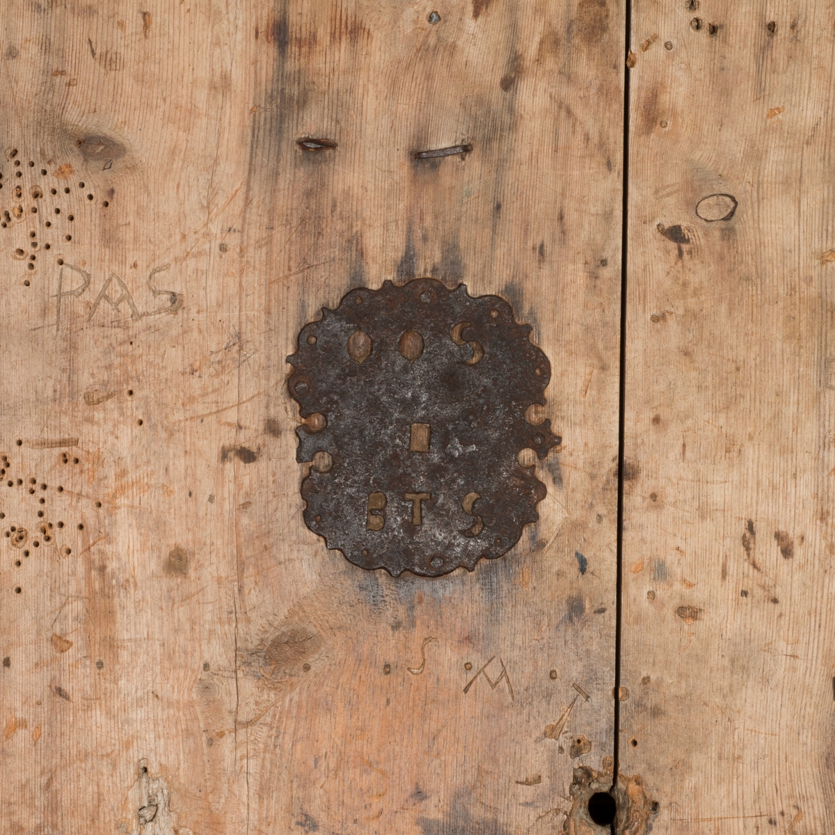 Døra består av tre planker på innsida, satt sammen med dragspon, som senere er høvla ned så døra er helt plan. Har jernbeslag på innsida, over dragspon, som fungerer som hengsler. 

Jernbeslag midt på døra på innsida, med bokstavene "OOS" og "BTS".

Jernlås festa med jernspiker. Nøkkelhullbeslag i jern. 

På utsida kledd med profilerte bord med not og fjær. Festa med jernnagler. 

Blåmalt på framsida. Ellers umalt. 

På begge sider spor der lås har vært innfelt. På innsida er dette fylt igjen med et trestykke.