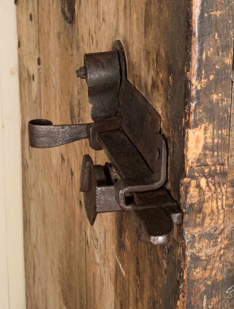 Døra består av tre planker på innsida, satt sammen med dragspon, som senere er høvla ned så døra er helt plan. Har jernbeslag på innsida, over dragspon, som fungerer som hengsler. 

Jernbeslag midt på døra på innsida, med bokstavene "OOS" og "BTS".

Jernlås festa med jernspiker. Nøkkelhullbeslag i jern. 

På utsida kledd med profilerte bord med not og fjær. Festa med jernnagler. 

Blåmalt på framsida. Ellers umalt. 

På begge sider spor der lås har vært innfelt. På innsida er dette fylt igjen med et trestykke.