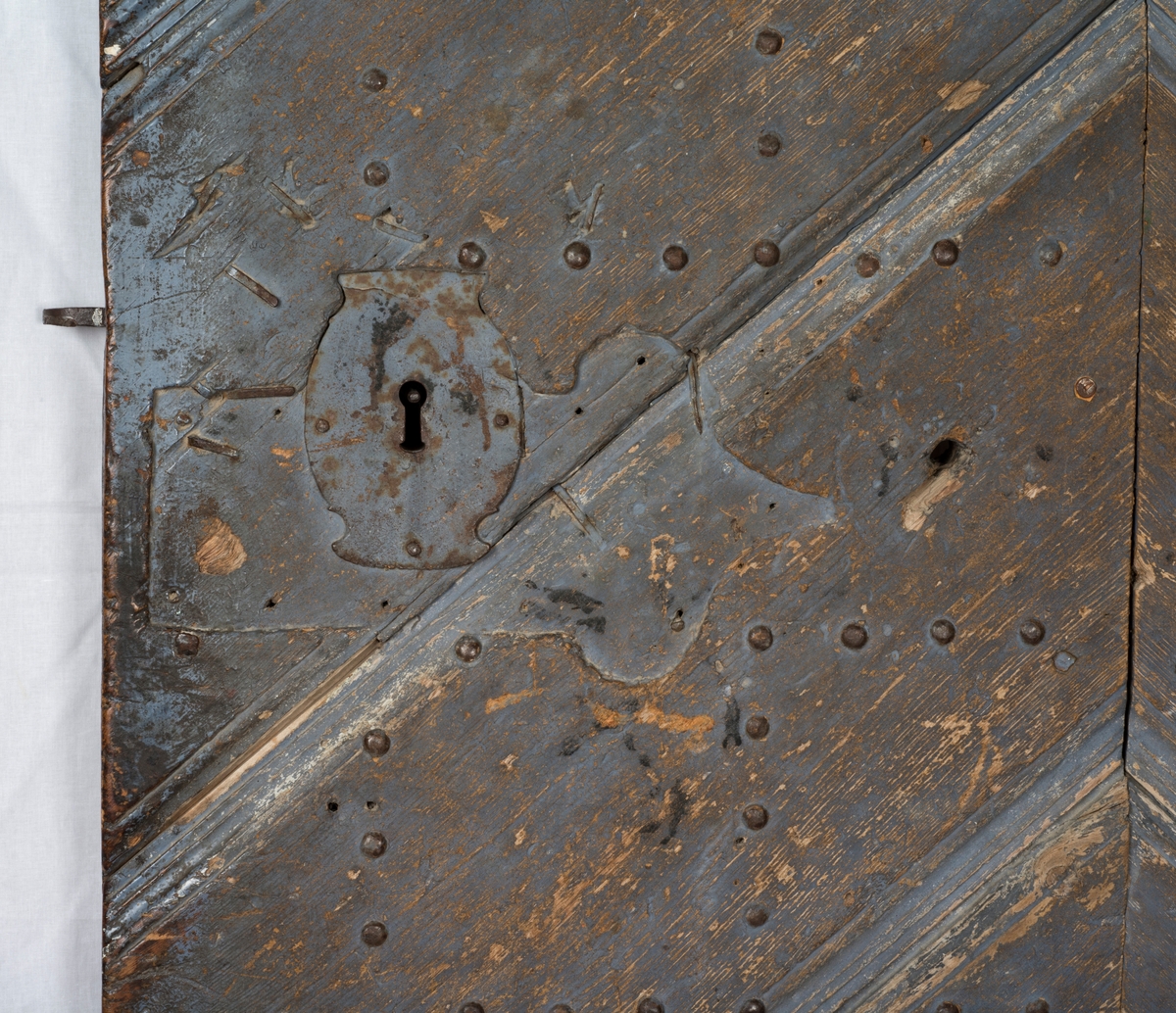 Døra består av tre planker på innsida, satt sammen med dragspon, som senere er høvla ned så døra er helt plan. Har jernbeslag på innsida, over dragspon, som fungerer som hengsler. 

Jernbeslag midt på døra på innsida, med bokstavene "OOS" og "BTS".

Jernlås festa med jernspiker. Nøkkelhullbeslag i jern. 

På utsida kledd med profilerte bord med not og fjær. Festa med jernnagler. 

Blåmalt på framsida. Ellers umalt. 

På begge sider spor der lås har vært innfelt. På innsida er dette fylt igjen med et trestykke.