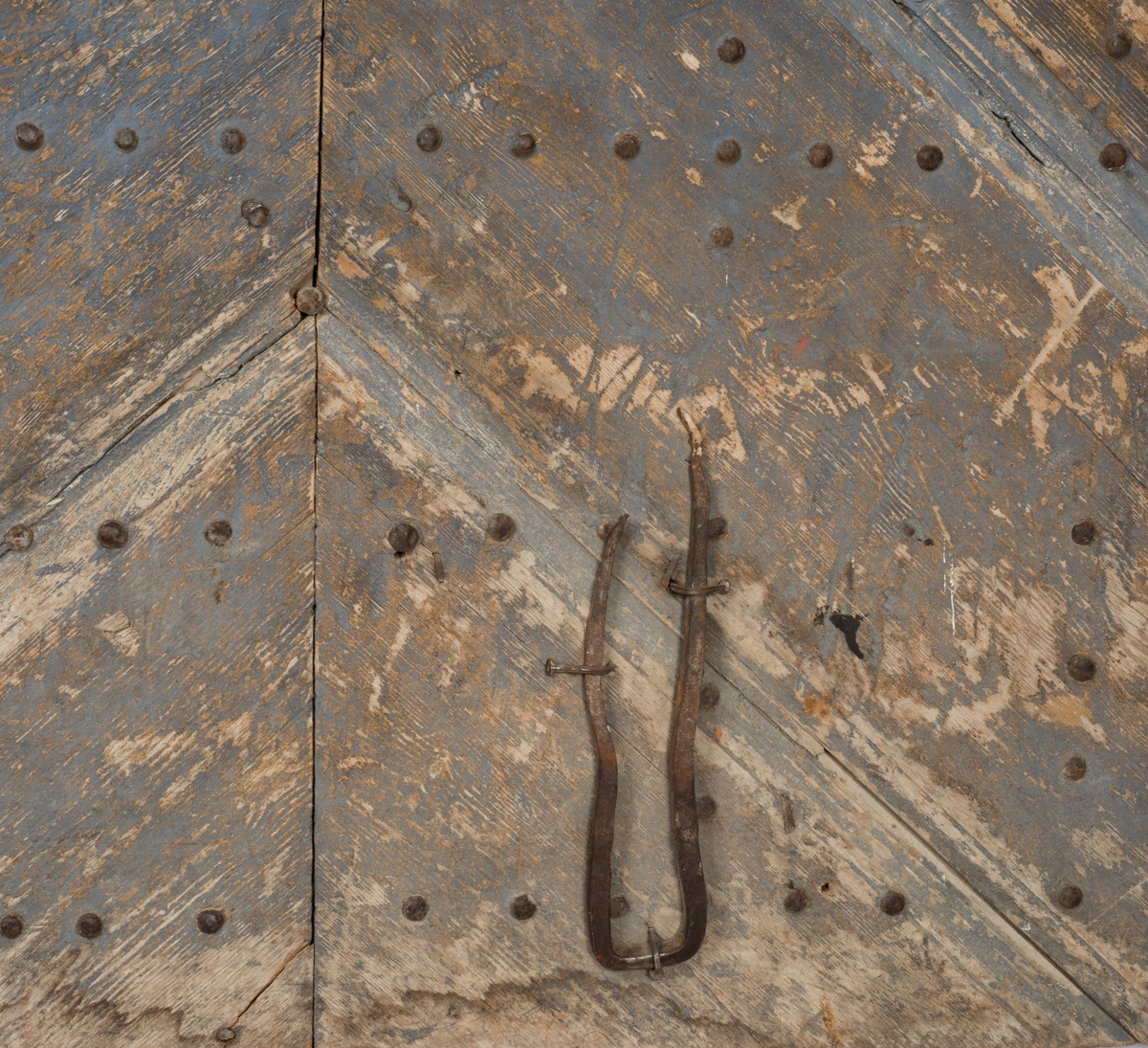 Døra består av tre planker på innsida, satt sammen med dragspon, som senere er høvla ned så døra er helt plan. Har jernbeslag på innsida, over dragspon, som fungerer som hengsler. 

Jernbeslag midt på døra på innsida, med bokstavene "OOS" og "BTS".

Jernlås festa med jernspiker. Nøkkelhullbeslag i jern. 

På utsida kledd med profilerte bord med not og fjær. Festa med jernnagler. 

Blåmalt på framsida. Ellers umalt. 

På begge sider spor der lås har vært innfelt. På innsida er dette fylt igjen med et trestykke.