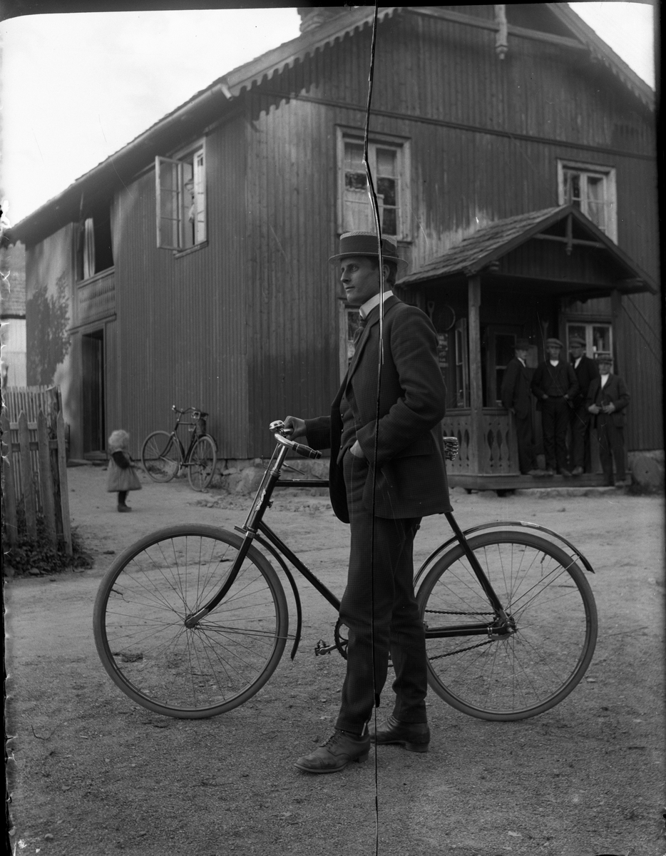 Fotosamling etter Kjetil Skomdal (1881-1971). Fotografen virket i perioden 1910 til 1960 og hadde eget mørkerom hvor han også tok imot film fra andre fotografer. I perioden var han også postbud i Fyresdal. Portrett av Sundt med sykkel.