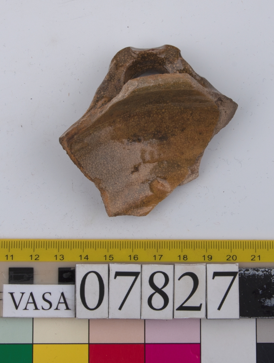 Del av skål.
1 st vertikal bandhänkel, tummad, 70 x 60 mm. Fragment av mynningsrand och buk. In- och utsida blyglaserad gulgrön.
