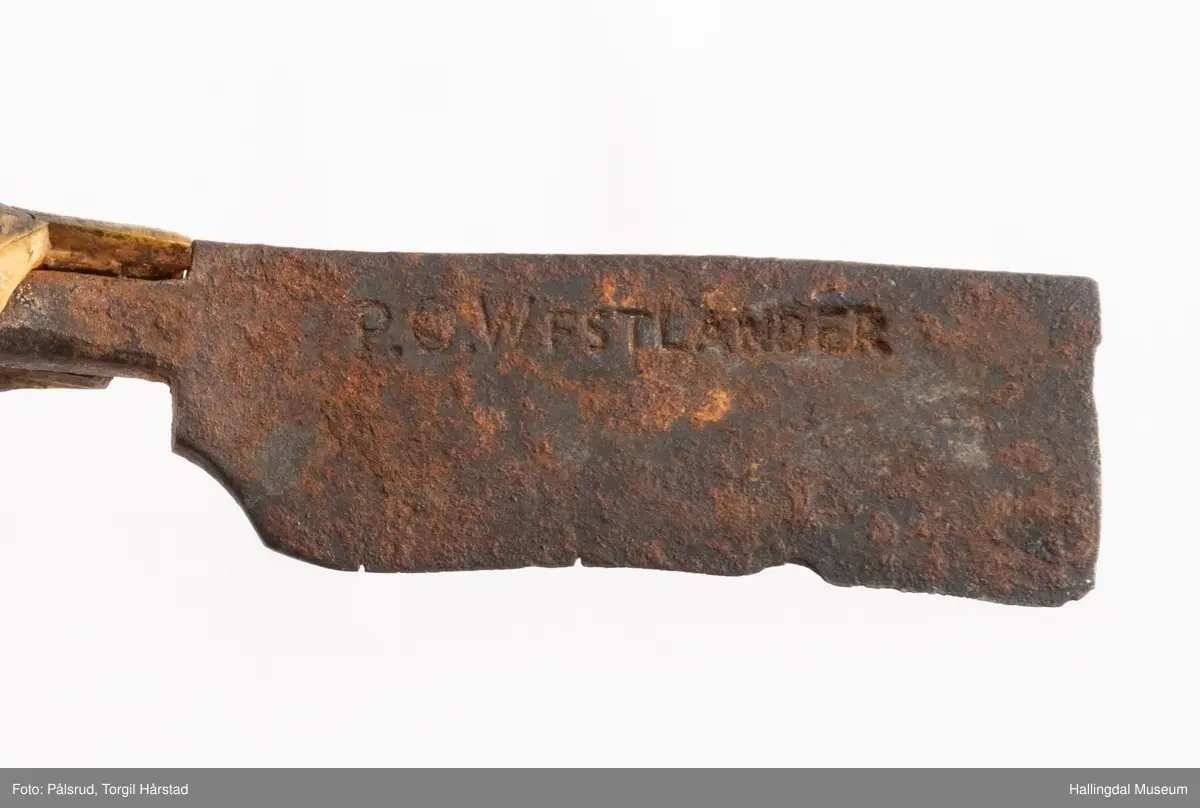 Kniv med etui. 
Etuiet er laget av mørkebrunt lær og ullstoff i grønt, rødt, gult og blått. Den er en tilnærmet rektangulær form som er avrundet i bunn og lokk. Er sydd sammen av to stykker med en ytterside og en innerside. Yttersiden er av mørkebrunt lær med påsydd lærkant. Den bredeste delen kan brettes over som lokk og har en utskjært hjerte- og en utskjært tulipanform. Lokket har på innsiden en lærreim som feste. Begge formene er kantet med lyse sting og foret med rødt ullstoff. 
På innsiden er etuiet foret med grønt ullstoff der de lyse stingene fra formene på lokket er synlig. kniven oppbevares i en av fire lommer som er kantet med grønt, gult, rødt og blått ullstoff. Selve yttersiden av etuiet/eller knivsliren er av mørkebrunt lær, kantet med samme lærkant som yttersiden og lokk, og er dekorert med linjer på sidene. Den er også dekorert med en påsydd lærlomme som er foret med rødt ullstoff som synes på kantene. Sydd med lyse sting og er preget med med et kryss og en V. 

Kniven har et skaft med et utskåret dyrehode (hvalross) og et laget av en hvalrosstann. Noe skadd. Knivbladet er festet gjennom hele lengden av skaftet, er rustent og har avbrekte deler på knivbladet. Knivblad stemplet med P. C./eller O. Westlander.