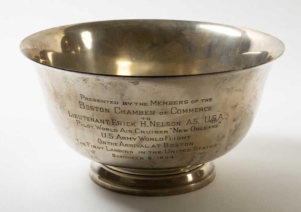 Bål av silver.  På bålens utsida står det ingraverat: "Presented by the members of the Boston chamber of commerce to Lieutenant Erik H Nelson a.s. USA pilot world air cruiser New Orleans UA army world flight on the arrival at Boston the first landing in the United States, spetember 6. 1924".