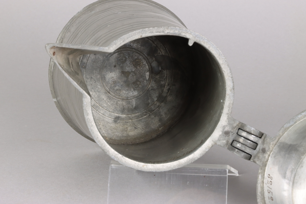 Jug and cover, all in pewter, with conical body  and a loop handle. On the cover knob in the form of a pine cone. On the body sections of horizontal borders. Five hallmarks inside the jug.
