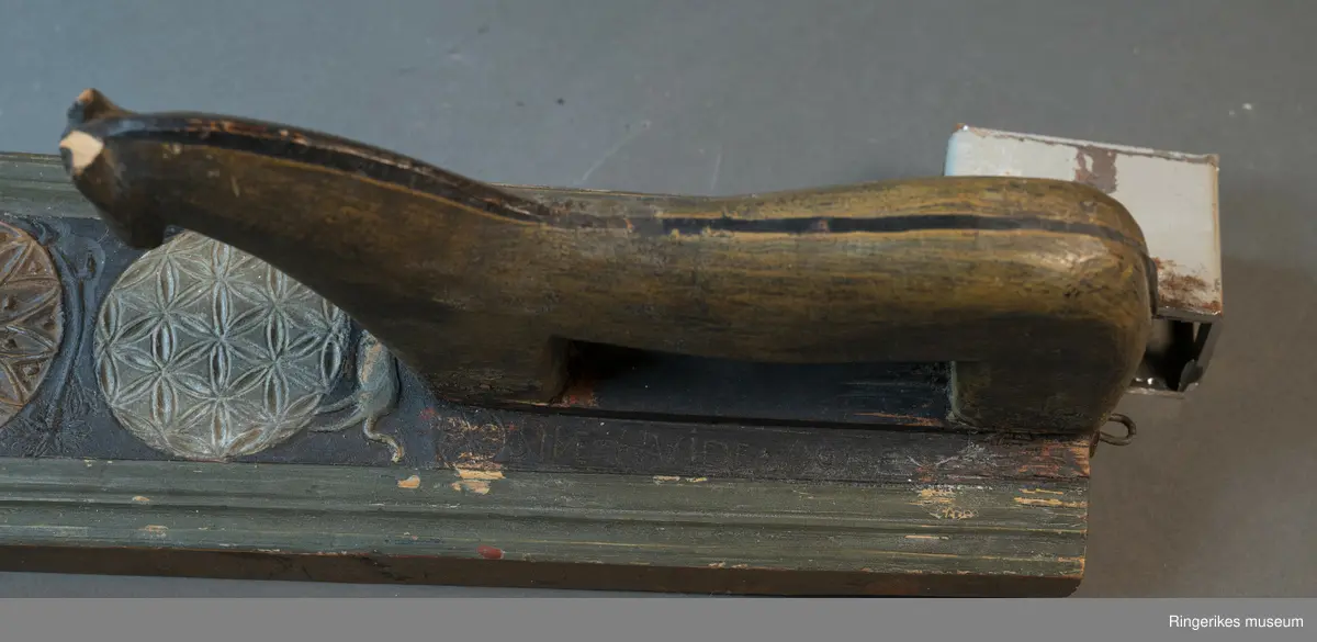 Laget av massivt tre med innfelt hest. Krok av jern i enden, antageligvis sekundær. Rester av lær festet med 3 spiker i enden, antagelig gammelt oppheng. Håndtaket er formet som en hest med man, hvite øyne, ører, og mule. Panneluggen er pent utskåret. Ett øre er ødelagt. Hesten har hale. Man og hale er malt svarte, og det går en svart strek langs ryggen til hesten fra man til hale. Denne er også svart. Halen er kort. Det er en sprekk mellom hesten og mangletreet. Rundt hesten er det innrisset skrift, og to små rosetter i karveskurd, diameter 1.5 cm. Relieff av hund foran hestens forbein. Hunden er malt i grågrønn farge. 

Det er 7 rosetter skåret ut på mangletreet. Hver rosett har sitt spesifikke mønster. Rosett 1,2,3,5,6 har blomstermønster. 4 og 7 har virvler. Annenhver rosett er malt med grågrønn, og annenhver med brun farge. Feltet rundt rosettene er malt svart, med noe utydelig dekor, og tallene 1808 mellom hver rosett fra 3. til 7. På motsatt side er bokstavene JSSS skåret inn. Mangletreet har et grønt felt utenfor det svarte, dette er skåret til en pen profil. Mangletreet bærer i det hele tatt preg av høy kvalitet på håndverket.