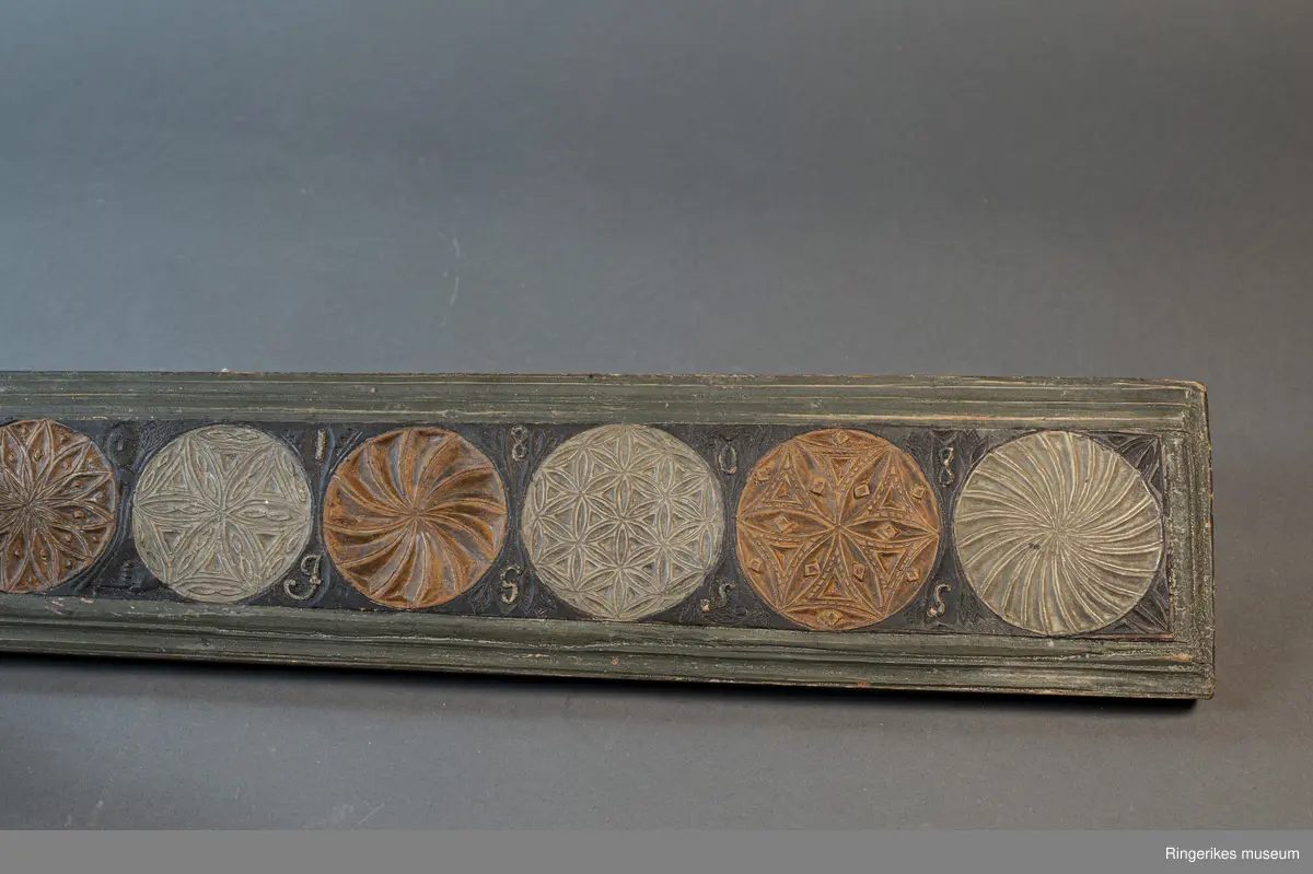 Laget av massivt tre med innfelt hest. Krok av jern i enden, antageligvis sekundær. Rester av lær festet med 3 spiker i enden, antagelig gammelt oppheng. Håndtaket er formet som en hest med man, hvite øyne, ører, og mule. Panneluggen er pent utskåret. Ett øre er ødelagt. Hesten har hale. Man og hale er malt svarte, og det går en svart strek langs ryggen til hesten fra man til hale. Denne er også svart. Halen er kort. Det er en sprekk mellom hesten og mangletreet. Rundt hesten er det innrisset skrift, og to små rosetter i karveskurd, diameter 1.5 cm. Relieff av hund foran hestens forbein. Hunden er malt i grågrønn farge. 

Det er 7 rosetter skåret ut på mangletreet. Hver rosett har sitt spesifikke mønster. Rosett 1,2,3,5,6 har blomstermønster. 4 og 7 har virvler. Annenhver rosett er malt med grågrønn, og annenhver med brun farge. Feltet rundt rosettene er malt svart, med noe utydelig dekor, og tallene 1808 mellom hver rosett fra 3. til 7. På motsatt side er bokstavene JSSS skåret inn. Mangletreet har et grønt felt utenfor det svarte, dette er skåret til en pen profil. Mangletreet bærer i det hele tatt preg av høy kvalitet på håndverket.