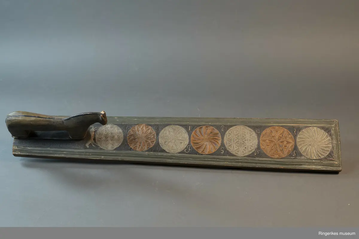 Laget av massivt tre med innfelt hest. Krok av jern i enden, antageligvis sekundær. Rester av lær festet med 3 spiker i enden, antagelig gammelt oppheng. Håndtaket er formet som en hest med man, hvite øyne, ører, og mule. Panneluggen er pent utskåret. Ett øre er ødelagt. Hesten har hale. Man og hale er malt svarte, og det går en svart strek langs ryggen til hesten fra man til hale. Denne er også svart. Halen er kort. Det er en sprekk mellom hesten og mangletreet. Rundt hesten er det innrisset skrift, og to små rosetter i karveskurd, diameter 1.5 cm. Relieff av hund foran hestens forbein. Hunden er malt i grågrønn farge. 

Det er 7 rosetter skåret ut på mangletreet. Hver rosett har sitt spesifikke mønster. Rosett 1,2,3,5,6 har blomstermønster. 4 og 7 har virvler. Annenhver rosett er malt med grågrønn, og annenhver med brun farge. Feltet rundt rosettene er malt svart, med noe utydelig dekor, og tallene 1808 mellom hver rosett fra 3. til 7. På motsatt side er bokstavene JSSS skåret inn. Mangletreet har et grønt felt utenfor det svarte, dette er skåret til en pen profil. Mangletreet bærer i det hele tatt preg av høy kvalitet på håndverket.