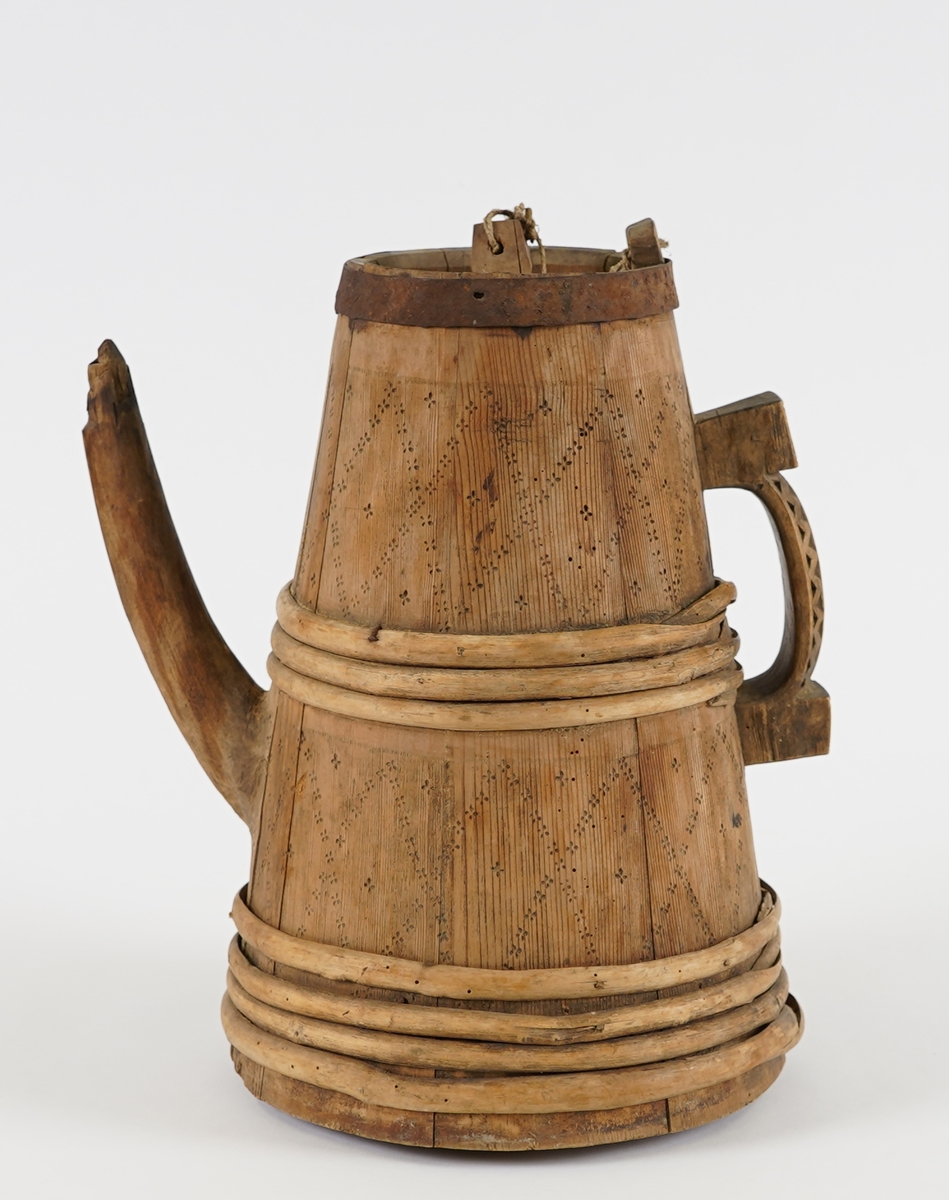 Ei lagga kanne, med konisk form. Sett saman av ti stavar og åtte vidjeband - sju av tre og eitt av jern. Den eine staven har ei uthola grein, som fungerer som tut på kanna. Staven på motsett side av denne har skore til ein hank av same stykke. Innfelt fast toppstykke med hol i midten, tetta med ein tapp som er knytt fast med hyssing i toppen av staven med hank. Svidekor på korpus, og utskjeringar på hanken.