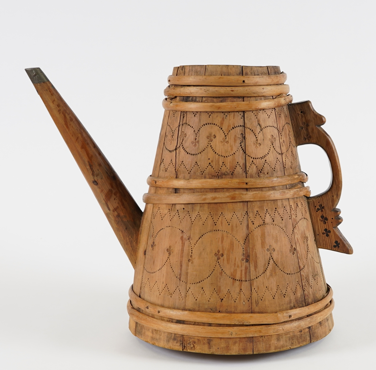 Ei lagga kanne, med konisk form. Sett saman av ti stavar og sju vidjeband. Den eine staven har ei uthola grein, som fungerer som tut på kanna. Staven på motsett side av denne har skore til ein hank av same stykke. Innfelt fast toppstykke med hol i midten. Svidekor på korpus og hanken.