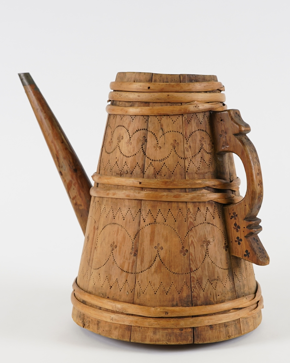 Ei lagga kanne, med konisk form. Sett saman av ti stavar og sju vidjeband. Den eine staven har ei uthola grein, som fungerer som tut på kanna. Staven på motsett side av denne har skore til ein hank av same stykke. Innfelt fast toppstykke med hol i midten. Svidekor på korpus og hanken.