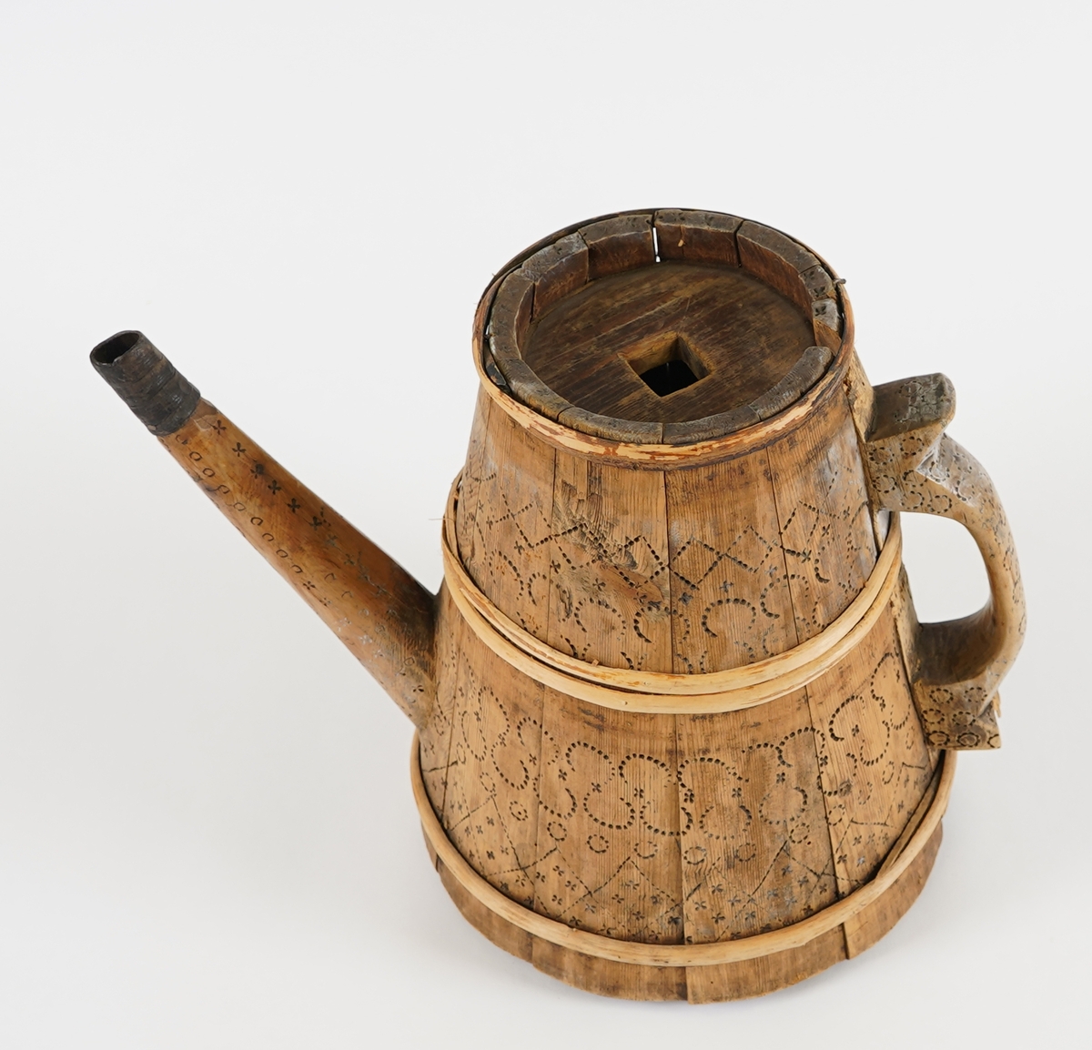 Ei lagga kanne, med konisk form. Sett saman av elleve stavar og tre vidjeband. Den eine staven har ei uthola grein, som fungerer som tut på kanna. Staven på motsett side av denne har skore til ein hank av same stykke. Innfelt fast topp- og botnstykke. Firkanta hol i midten av toppstykket. Svidekor på heile utsida.