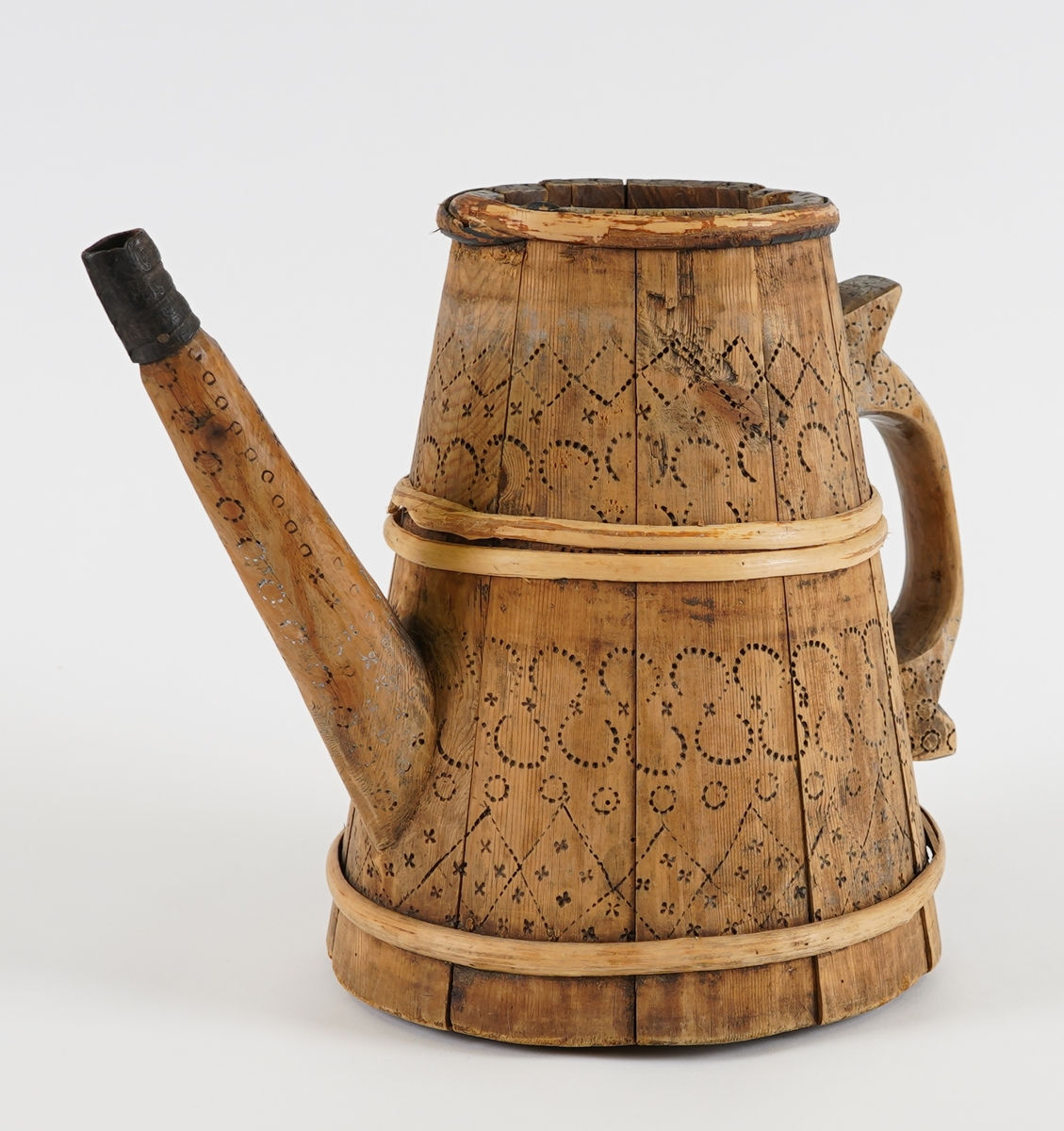 Ei lagga kanne, med konisk form. Sett saman av elleve stavar og tre vidjeband. Den eine staven har ei uthola grein, som fungerer som tut på kanna. Staven på motsett side av denne har skore til ein hank av same stykke. Innfelt fast topp- og botnstykke. Firkanta hol i midten av toppstykket. Svidekor på heile utsida.