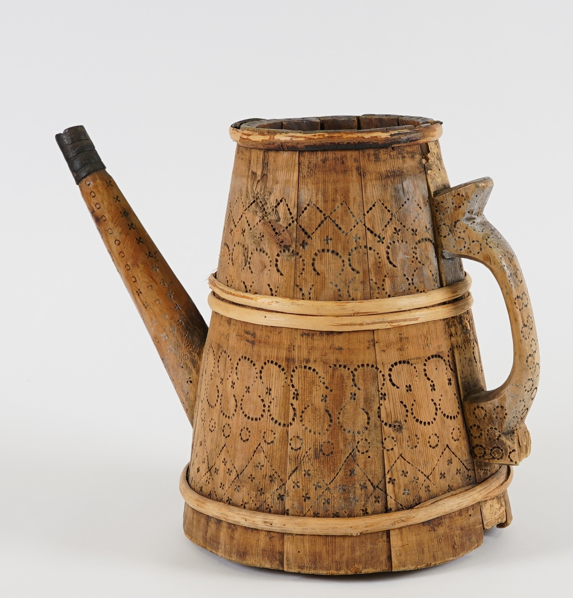 Ei lagga kanne, med konisk form. Sett saman av elleve stavar og tre vidjeband. Den eine staven har ei uthola grein, som fungerer som tut på kanna. Staven på motsett side av denne har skore til ein hank av same stykke. Innfelt fast topp- og botnstykke. Firkanta hol i midten av toppstykket. Svidekor på heile utsida.