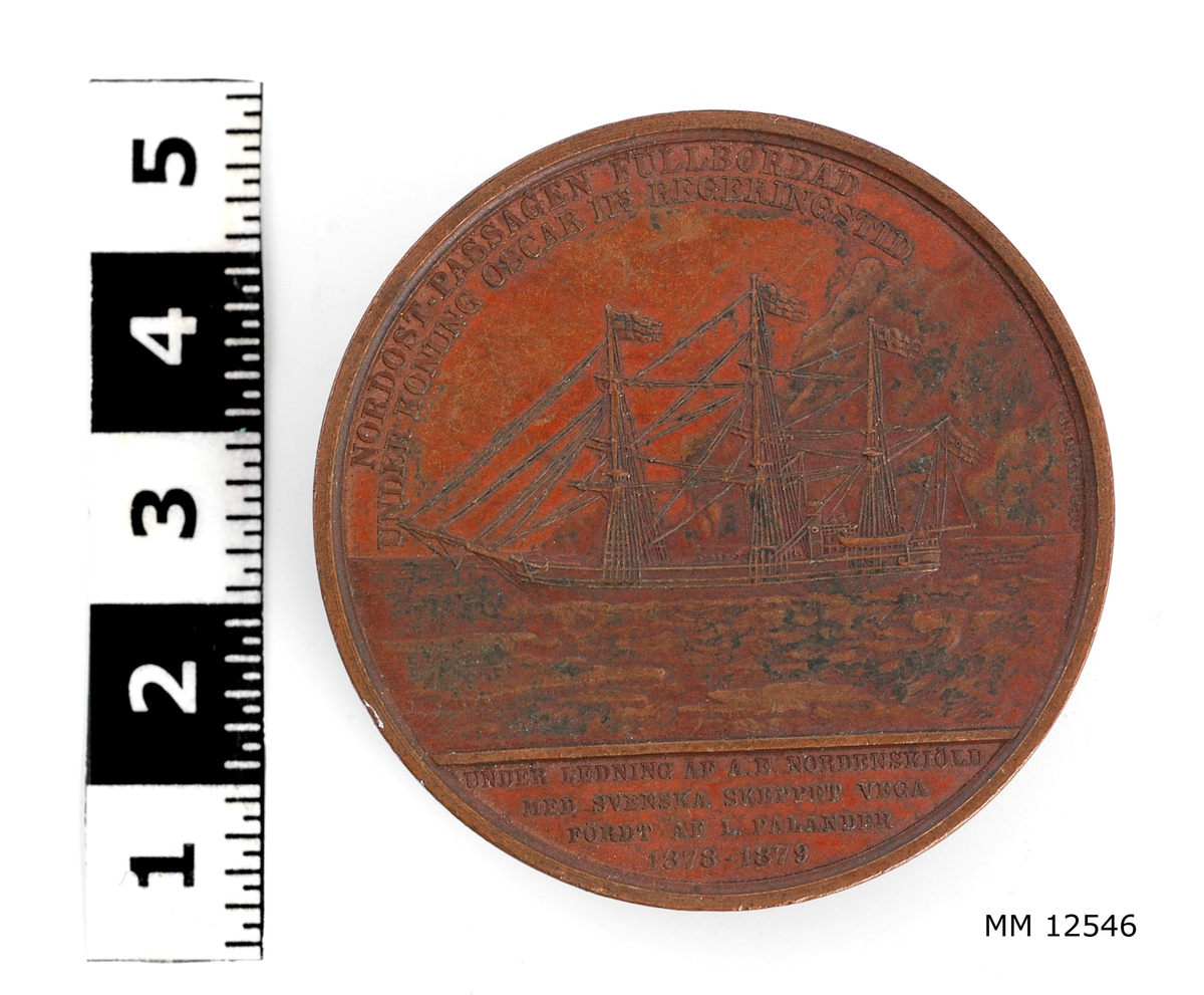 Minnespenning i koppar över nordostpassagen 1878-1880 med skeppet Vega.

På ena sidan är skeppet Vega avbildat (f.d. norskt sälfångstfartyg) med texten: "Nordost-passagen fullbordad under Konung Oscar II:s regeringstid under ledning af A. E. Nordenskiöld med svenska skeppet Vega fördt af L. Palander 1878-1879"

På andra sidan finnes en sektor av jorden med norrsken samt därunder texten: "Af officerare och civila tjänstemän vid Kongl. Flottan."