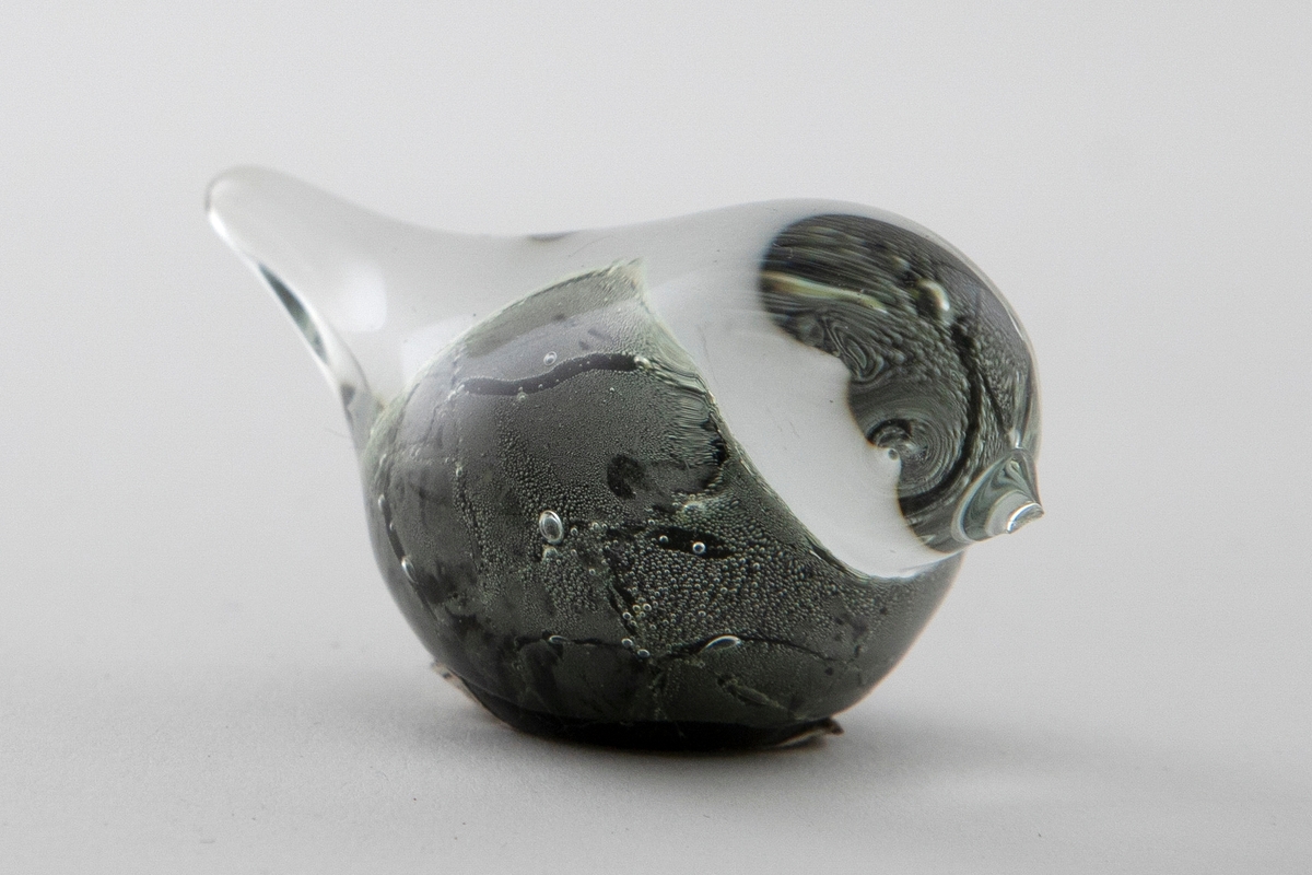 Glassfigur i klart og sortfarget opakt glass. Stilisert fugleform samt luftbobler.