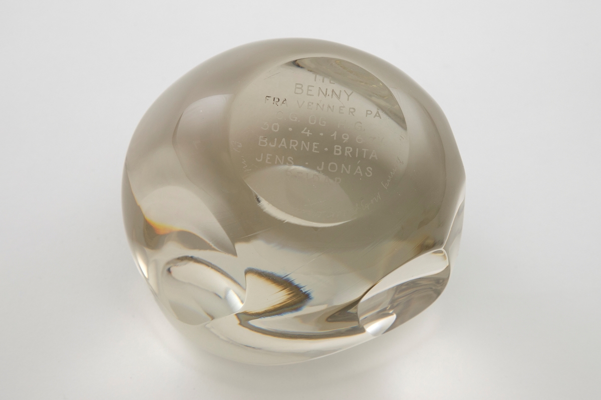 Irregulær kuleformet skulptur av massiv klart glass med slipte ovalformede og runde partier på yttersiden.