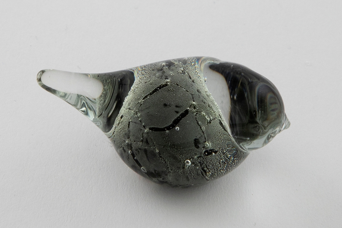 Glassfigur i klart og sortfarget opakt glass. Stilisert fugleform samt luftbobler.