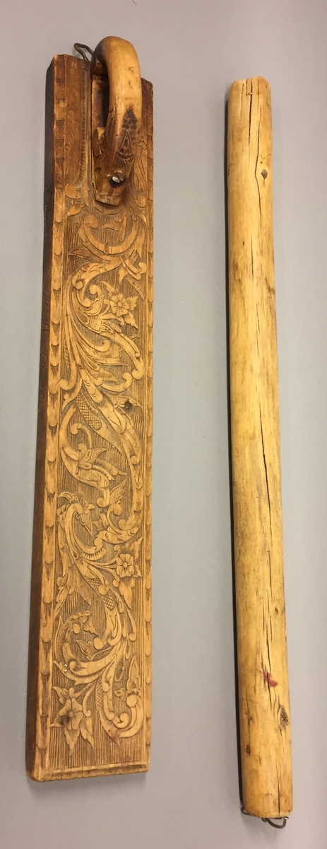 Mangletre med kjevle. Handtak med skoren rosedekor. Handtaket er festa til mangletreet med ein skrue truleg sekundært. Rankedekor i flatskurd. Blomar og c-krullar, Kjevlet er ein rund stokk utan dekor. Det er sett på hemper til oppheng på både mangletreet og kjevlet. På sida av mangletreet er det skore inn bokstavane TÅD(TAD?). Det er òg rissa inn nokre bokstavar, desse er utydlege men den første er truleg ein Ø.
