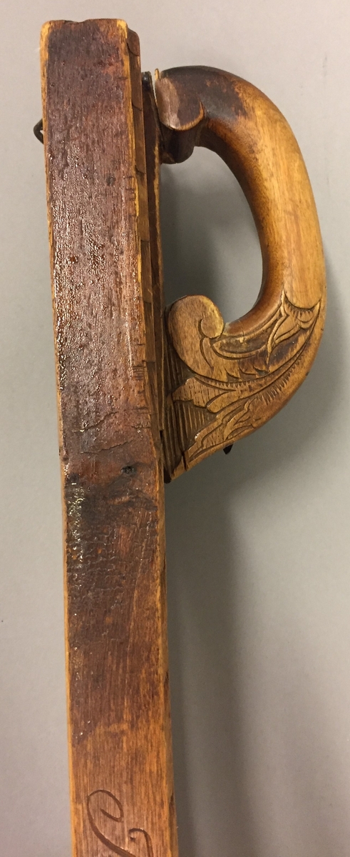 Mangletre med kjevle. Handtak med skoren rosedekor. Handtaket er festa til mangletreet med ein skrue truleg sekundært. Rankedekor i flatskurd. Blomar og c-krullar, Kjevlet er ein rund stokk utan dekor. Det er sett på hemper til oppheng på både mangletreet og kjevlet. På sida av mangletreet er det skore inn bokstavane TÅD(TAD?). Det er òg rissa inn nokre bokstavar, desse er utydlege men den første er truleg ein Ø.