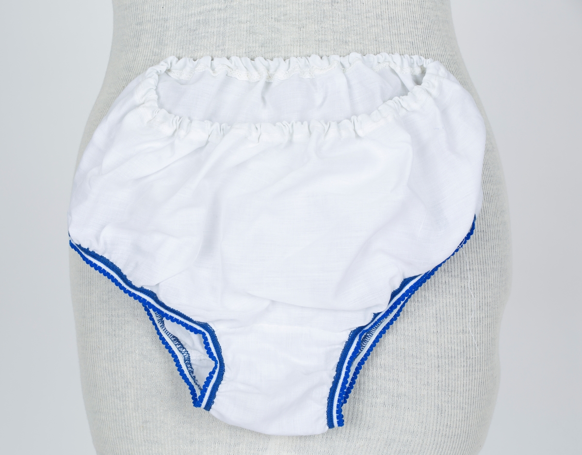 Baby doll. 2-delt nattøy. Stoff i tynn polyester/bomullsblanding, hvit bunn med blå blomstertrykk
A: Overdel
Firkantet hvitt bærestykke og halsåpning. Sommerfugl rysj over skulder. "skjørt" lett rynket til bærestykket. Smal sløyfe av stoffet midt på bærestykket.
B: Truse
Hvit, Blå strikkanter i livet og rundt benåpning.