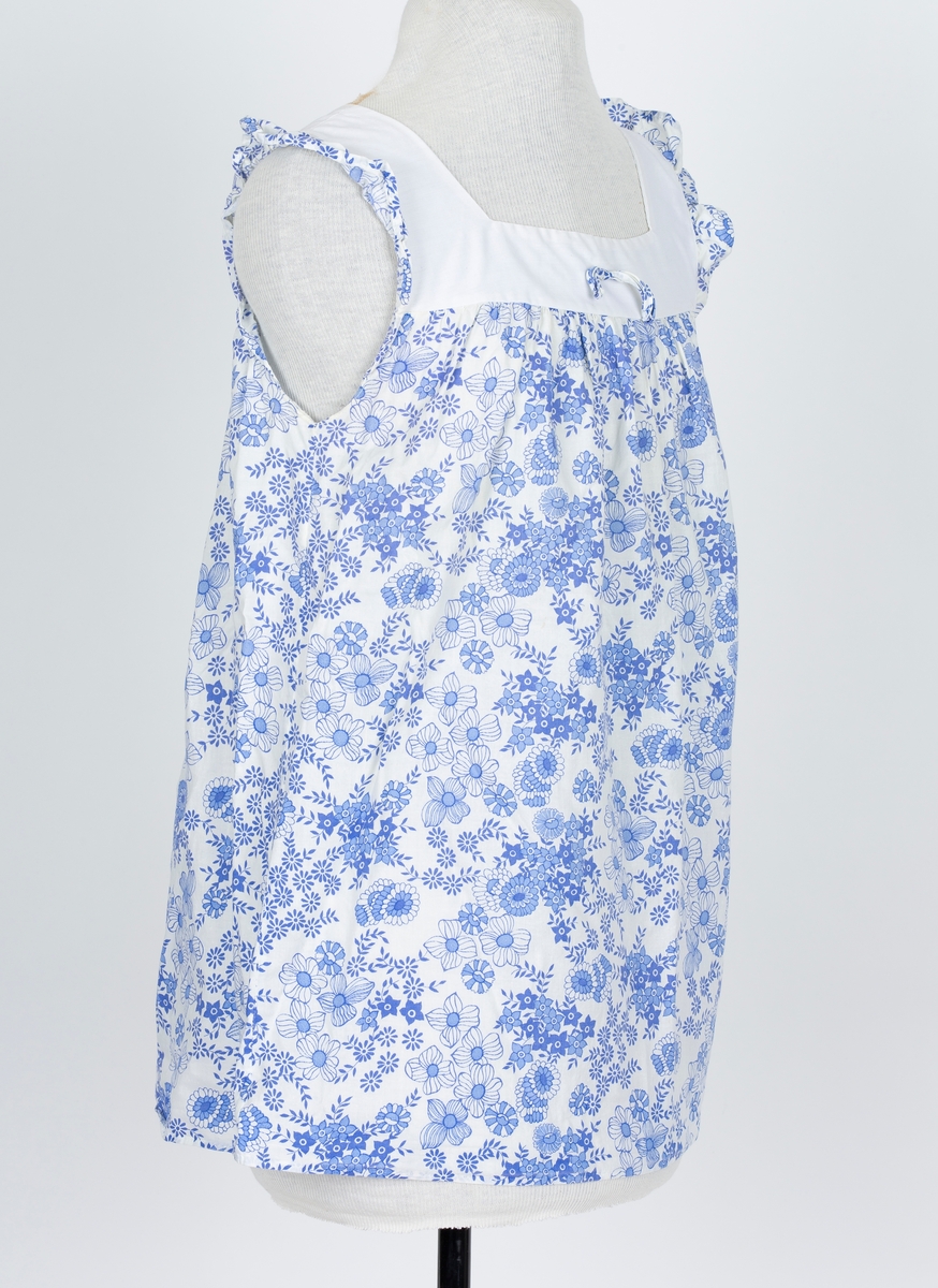 Baby doll. 2-delt nattøy. Stoff i tynn polyester/bomullsblanding, hvit bunn med blå blomstertrykk
A: Overdel
Firkantet hvitt bærestykke og halsåpning. Sommerfugl rysj over skulder. "skjørt" lett rynket til bærestykket. Smal sløyfe av stoffet midt på bærestykket.
B: Truse
Hvit, Blå strikkanter i livet og rundt benåpning.
