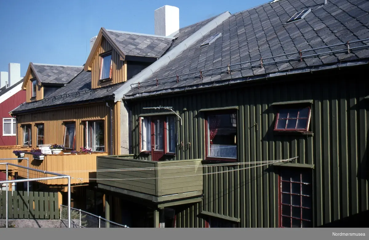 Konsul Johnsens gate. påbygde balkonger bak. Prosjektet Dokument 2000 - Kristiansund ved årtusenskiftet, år 1999/2000. Nordmøre Museum har i samarbeid med seks medlemmer av Kristiansund Kameraklubb og Fylkeskonservatorens bygningsantikvar gjennomført en omfattende dokumentasjon av Kristiansund sentrum; hovedsakelig ”gjenreisningsbyen”.  Fotografene Reidun Furseth, Hans Ohrstrand, Ole Didriksen, Lena Hasselø, Britt Valderhaug Tyrholm og Peder Botten har særlig konsentrert seg om bygningsdetaljer som dører, vinduer, fasader, skilt, fargesetting og gaterom etter lister satt opp i samråd med fylkeskonservatorens bygningsantikvar Christ Allan Sylthe. I enkelte tilfeller har fotografen fått tillatelse til også å fotografere bygningene innvendig, og har fått med detaljer som skapdørlåser og blandebatterier. Mange samtids-detaljer folk flest sjelden legger merke til, er her dokumentert på en unik måte. Til sammen er omfatter arkivet 760 bilder. Det er Ole Didriksen som har tatt dette bildet.