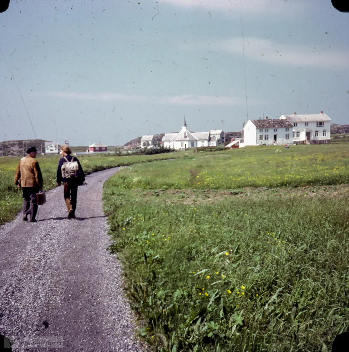 Sandøya: f.v: Torstein og Elna Vollen (kvitt hus), Kristian og Dagrunn (raudt hus), Olav og Berta Sandøy( grønt hus), Sandøy kyrkje, Øyvind og Astrid Sandøy (lysegrønt hus), Laurits og Anna Sandøy (kvitt hus) Gamleskulen..Biletet er tatt rett nord for Påskhelltunet, mot nordvest.