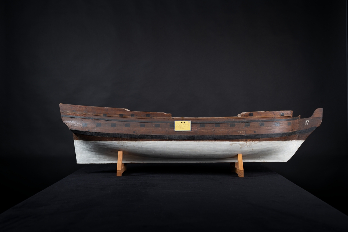 Fartygsmodell 40-kanonfregatt efter 1765 års reglemente. Skrovmodell. Bordläggningen limmad på gavlar, utan inredning, galjon och akterspegel. Modellen brunmålad med svarta kanonportar och under vattenlinjen vitmålad.