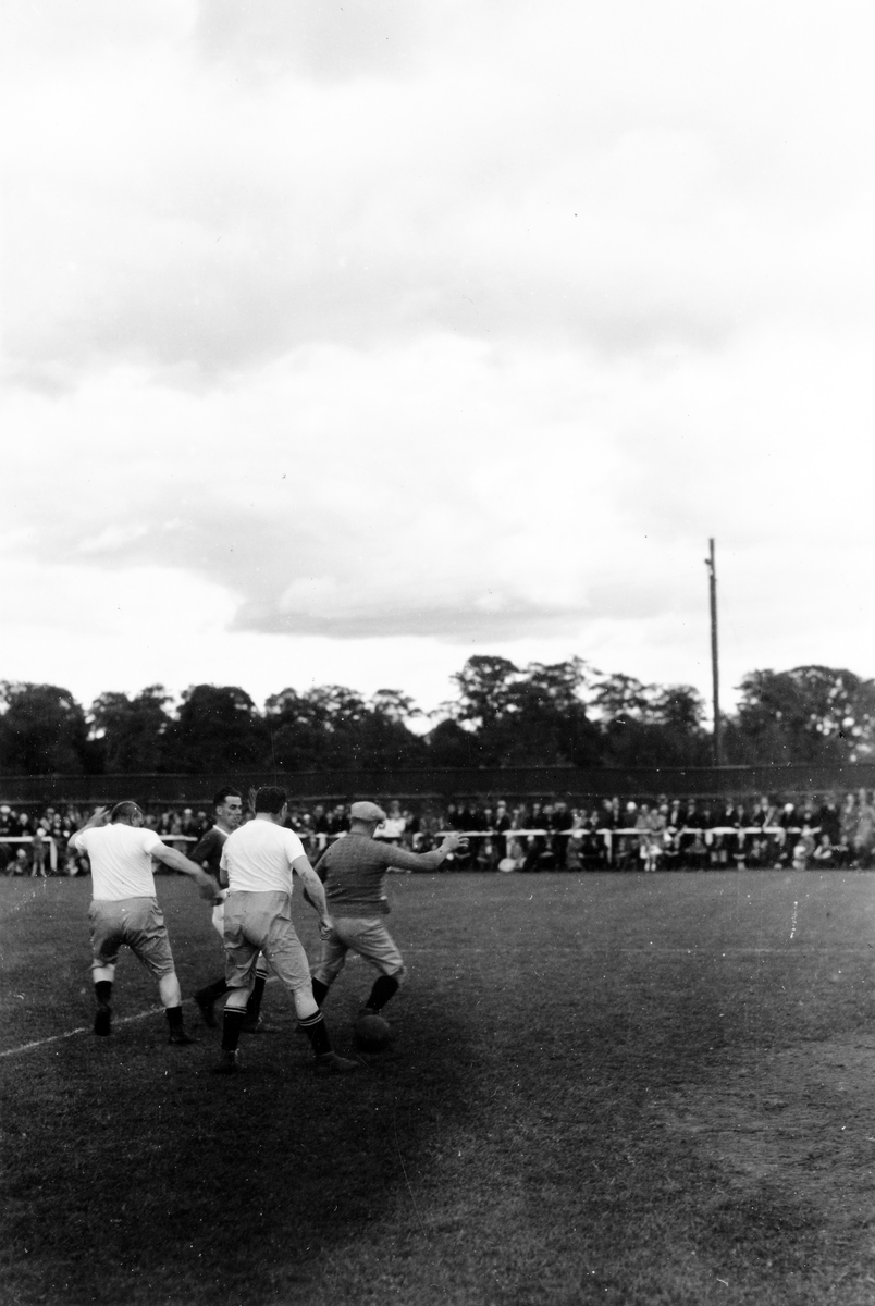 Barnens dag 1938. Fyra män spelar fotboll, barn och andra åskådare tittar på.