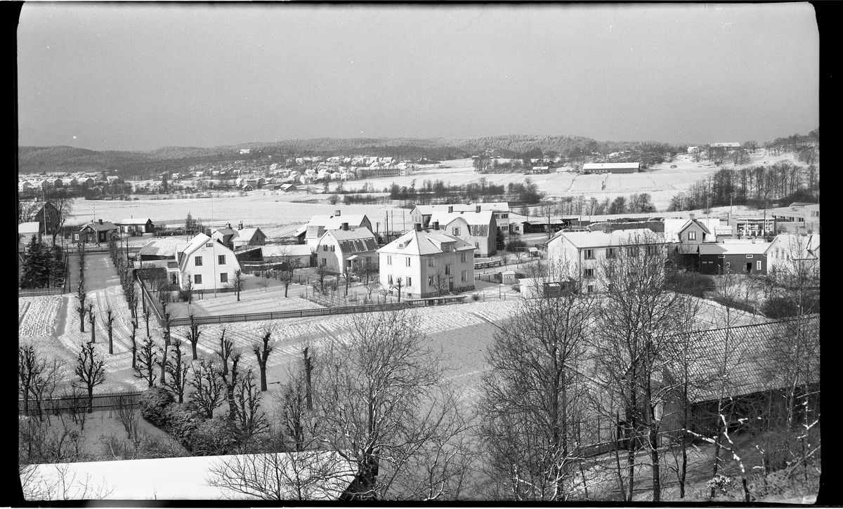 Utsikt mot Nolby från Häradsberget.

Flera stora flerfamiljs- och enfamiljshus, flertalet av trä.

Ett tunt snötäcke ligger över gräsmattor och åkermark.

Några trädgårdar är omgärdade med staket, spälstaket.
