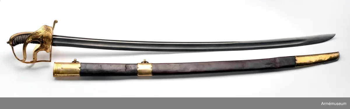 Sabeln är lik modellsabeln AM 36629, men avviker i frågan om fästets ornering. Den på kappan kring nitknappen anbringade ciselerade kransen är här större och går ned på ryggbeslaget och den på yttersidans parerplåt anbringade skölden med tre kronor är här större, ej krökt, nära nog cirkelrund och de sillerade palm- och lagerkvistar, som omger denna sköld, är här vida större och går in på ytterspängerna. Egendomligt nog finns såväl i Livrustkammaren som i ingenjör Orres samling sablar av denna typ, som på klingan har svenska riksvapnet med hessiska hjärtvapnet.