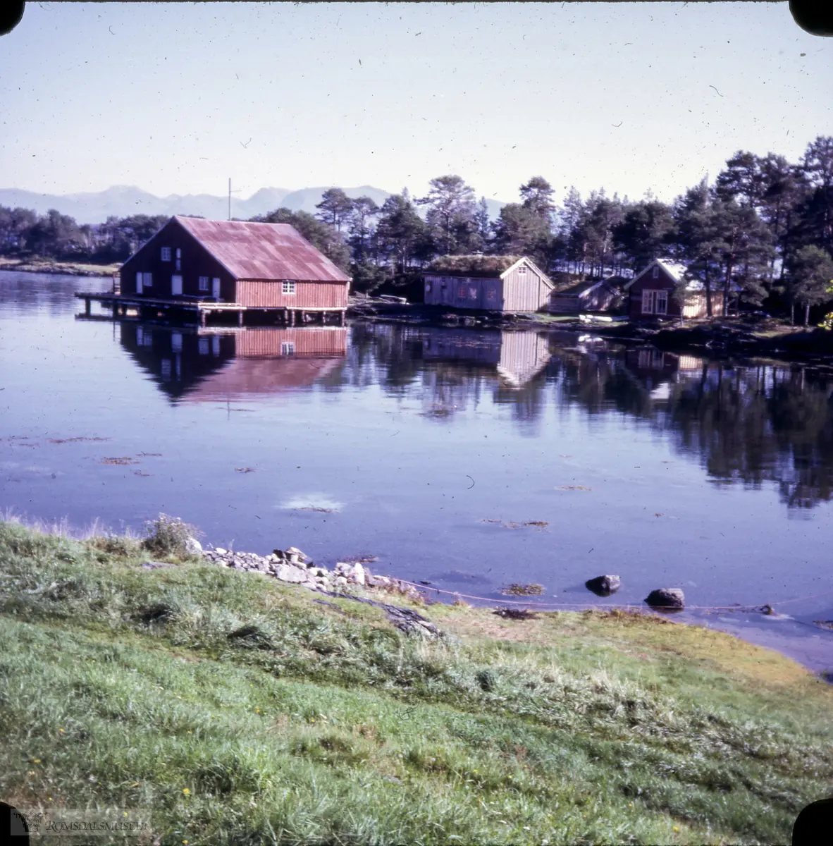 Fiskerimuseet på Hjertøya sett frå Hjertøybukta. F.v. Tranbrenneriet frå Husøya, Bjørneremstua, kjøkkenet til Fiskerangen og Solem skole. Solem skole var seinare flytt vestover for at det skulle bli plass til Røssøyvågen slip- og mekanisk verkstad først i 1980-åra.