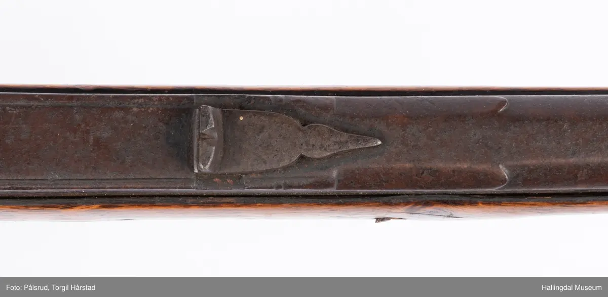 Gevær med perkusjonslås og kassepipe. Har mest sannsynlig vært ombygd fra flintlås. Geværet har kassepipe - har firkantet løp bakerst fra låsen til siktet midt på løpet. Fra låsen til siktet midt på løpet er løpet kasseformet og har en dekorert overgang til et svakt avrundet åttekantet løp. Det fremste siktet er av messing. Kolbekappen er festet med to skruer. Mangler avtrekksbøyle, reim og ladestokk. Montert på patentsvansskrue ved ombygging. Løpet er 15 cm i diameter og glattløpet.
