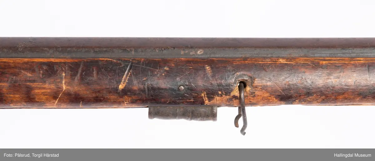 Gevær med perkusjonslås og kassepipe. Har mest sannsynlig vært ombygd fra flintlås. Geværet har kassepipe - har firkantet løp bakerst fra låsen til siktet midt på løpet. Fra låsen til siktet midt på løpet er løpet kasseformet og har en dekorert overgang til et svakt avrundet åttekantet løp. Det fremste siktet er av messing. Kolbekappen er festet med to skruer. Mangler avtrekksbøyle, reim og ladestokk. Montert på patentsvansskrue ved ombygging. Løpet er 15 cm i diameter og glattløpet.