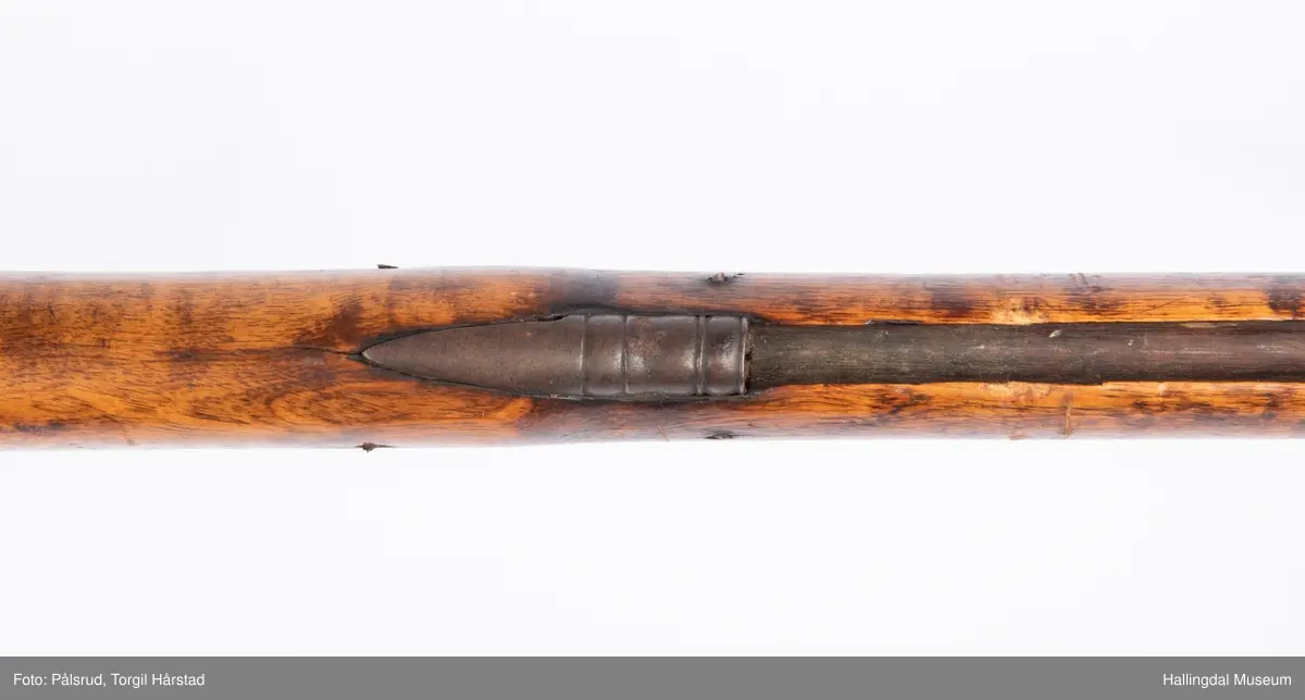 Gevær med perkusjonslås og kassepipe. Har mest sannsynlig vært ombygd fra flintlås. Geværet har kassepipe - har firkantet løp bakerst fra låsen til siktet midt på løpet. Fra låsen til siktet midt på løpet er løpet kasseformet og har en dekorert overgang til et svakt avrundet åttekantet løp. Det fremste siktet er av messing. Kolbekappen er festet med to skruer. Mangler avtrekksbøyle, reim og ladestokk. Montert på patentsvansskrue ved ombygging. Løpet er 15 cm i diameter og glattløpet.