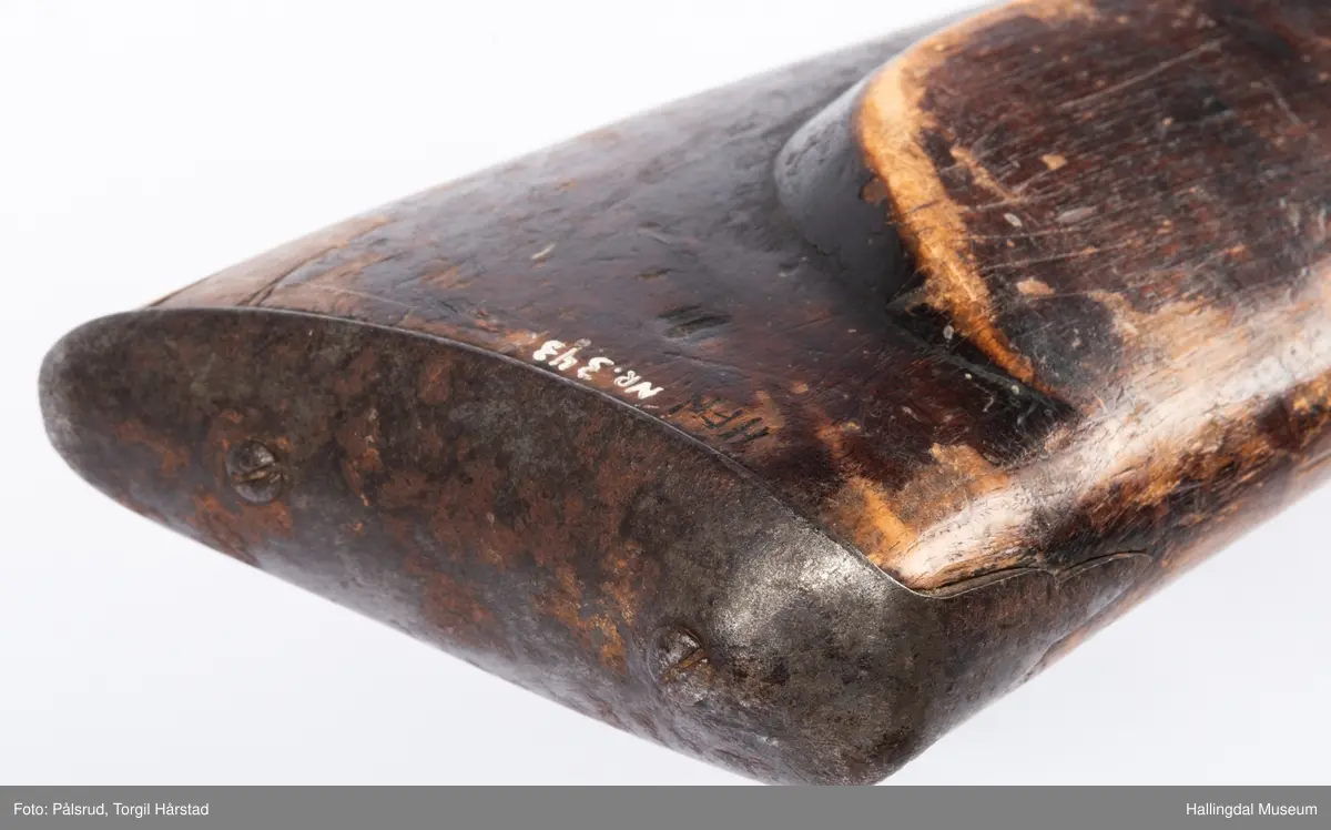 Gevær med perkusjonslås og kassepipe. Har mest sannsynlig vært ombygd fra flintlås. Geværet har kassepipe - har firkantet løp bakerst fra låsen til siktet midt på løpet. Fra låsen til siktet midt på løpet er løpet kasseformet og har en dekorert overgang til et svakt avrundet åttekantet løp. Det fremste siktet er av messing. Kolbekappen er festet med to skruer. Mangler avtrekksbøyle, reim og ladestokk. Montert på patentsvansskrue ved ombygging. Løpet er 15 cm i diameter og glattløpet.