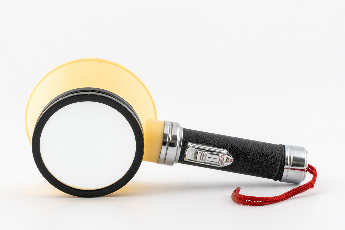 Lupe med skaft, skjerm og lampe med rød tråd for oppheng. Har tilhørt Sara Fabricius.