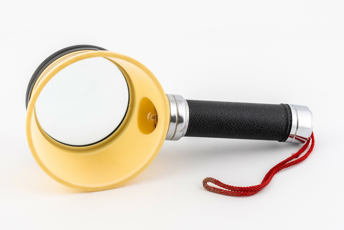 Lupe med skaft, skjerm og lampe med rød tråd for oppheng. Har tilhørt Sara Fabricius.